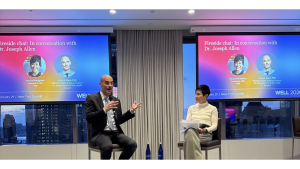 Two people seated and talking on a stage