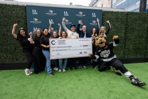 Group stands on a branded step-and-repeat holding a large donation check for the Culinary Careers Program at LA LIVE
