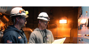 Two people wearing hard hats working in power plant