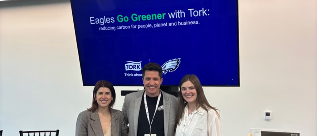 Three people standing in front of presentation. Screen behind says