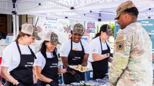 service member lining up for a lunch that was prepared by the Hunt.Fish.Feed. culinary team and Comcast Team UP volunteers